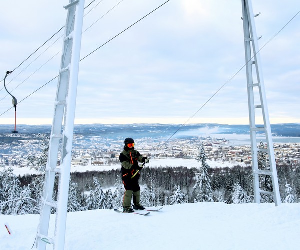 en skidåkare som åker lift med utsikt över en stad i bakgrunden