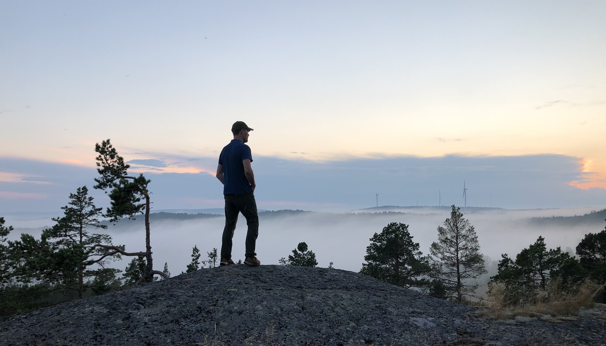 en man med keps står högst upp på en bergstopp