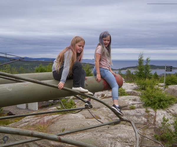 två flickor sitter på ett stort kanonrör