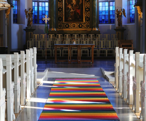 en altargång där det ligger en randig flerfärgad matta