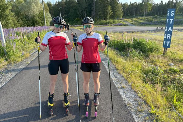 två rullskidåkare står på en asfalterad bana