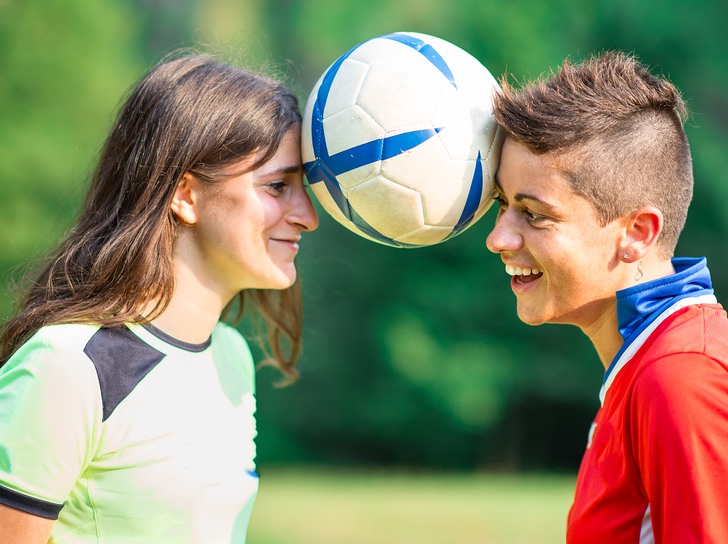 två ungdomar har en fotboll mellan sina pannor