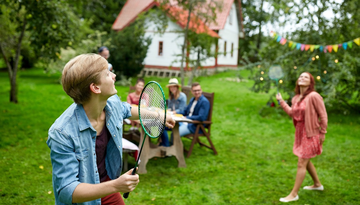 två personer spelar badminton i en trädgård