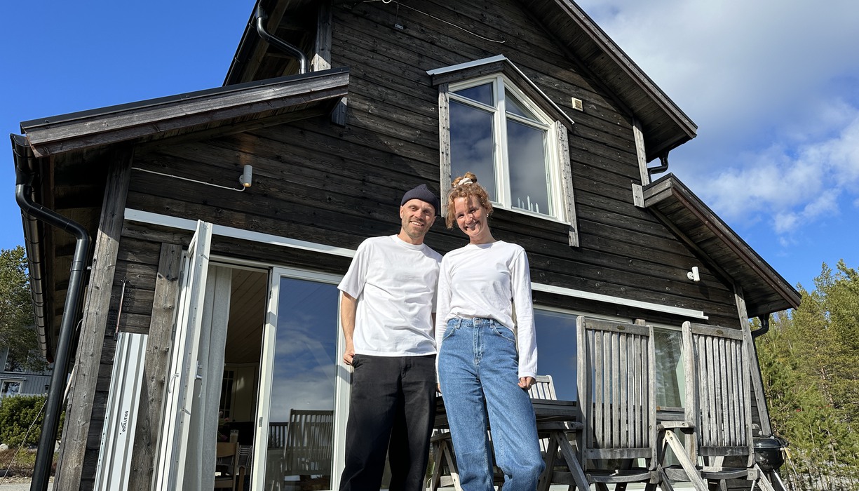 ett par står framför ett brunt hus.
