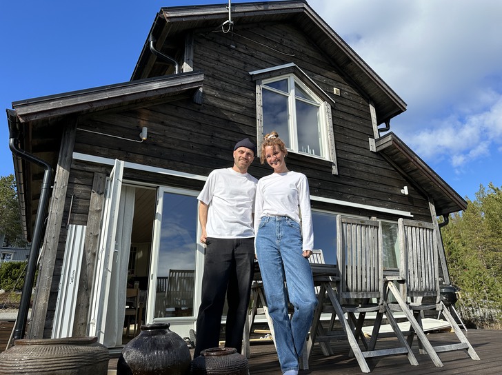 två personer står framför ett brunt hus
