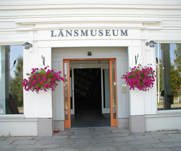 en entré med blombuketter på var sida om dörren. Ovanför porten står det Länsmuseum.