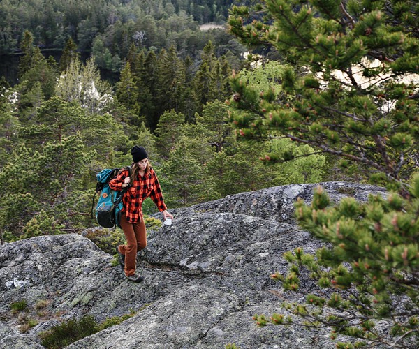 en ung kvinna med ryggsäck går uppför ett berg