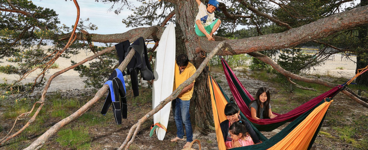 En familj som campar utomhus i hängmattor. 