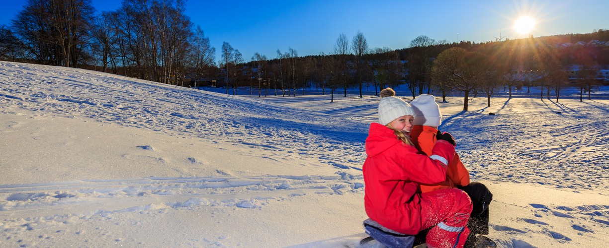 två barn sitter på en kölke i vintermiljö