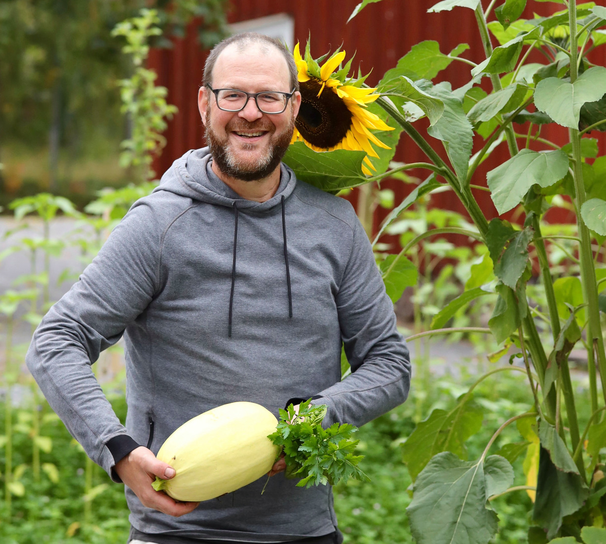 en man håller i en pumpa i en trädgård