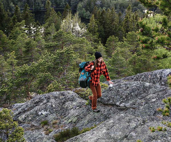 en ung kvinna med ryggsäck går uppför ett berg