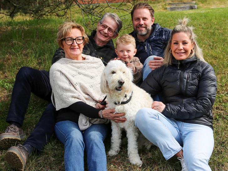 Fem personer och en hund sitter i en grässlänt