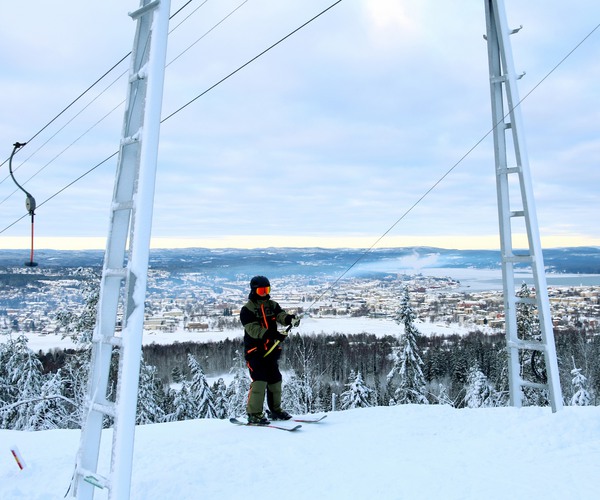 en person åker skidlift med utsikt över en stad i bakgrunden