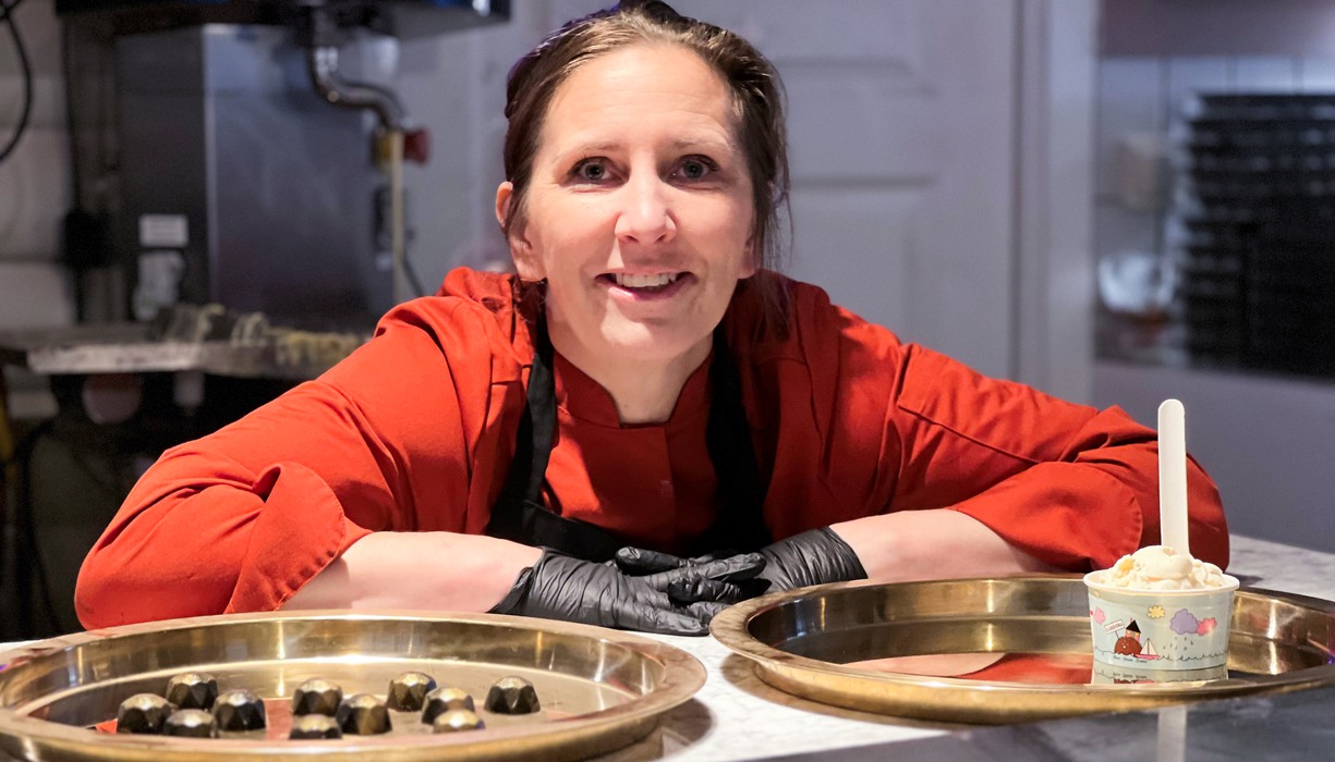 en kvinna står lutad vid en bänk med brickor med chokladpraliner