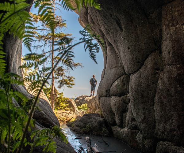 en grotta  sedd inifrån med en person utanför grottan i bakgrunden