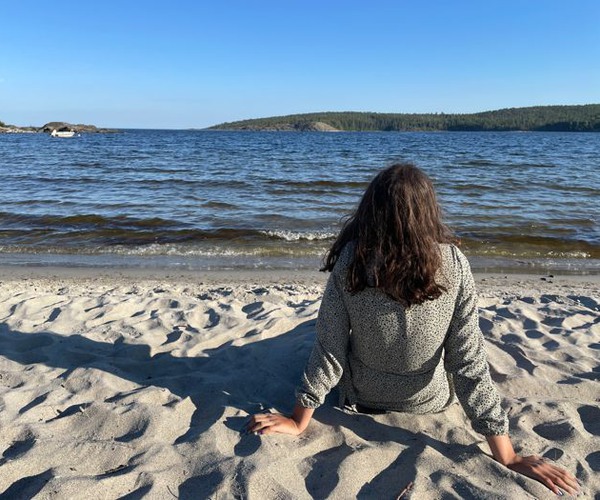 Ung tjej sitter och tittar mot havet på Sågsand
