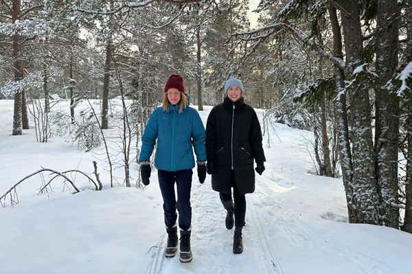 två personer promenerar i en skog i vintermiljö