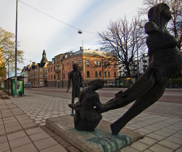 en skulptur i förgrunden vid en bred gata