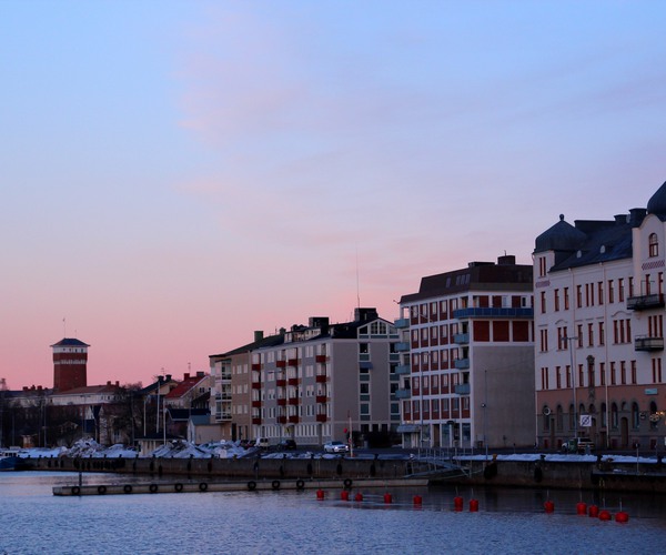 hus på rad längs en kaj med ett torn i bakgrunden